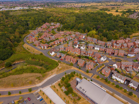 Barlaston, United Kingdom - 16 August 2026: Aerial view of the residential neighborhood near the World of Wedgwood, featuring rows of red brick houses, winding streets, and surrounding woodland.
