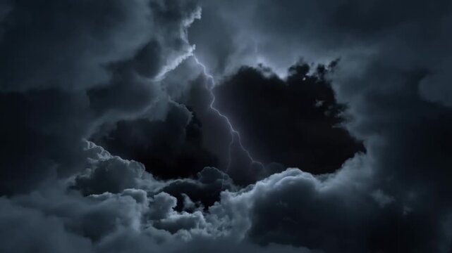 Lightning flashes through dark storm clouds with glowing cloud edges at night