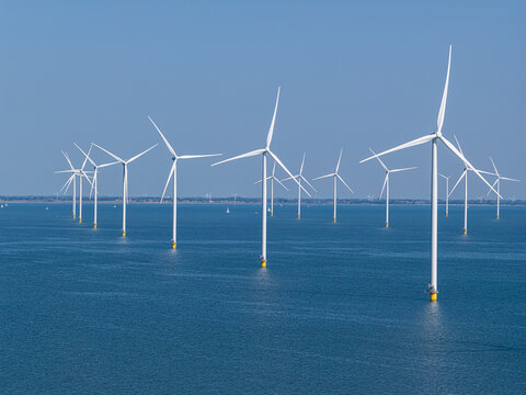 Aerial view of offshore wind turbines standing in the calm blue water of the IJsselmeer near Breezanddijk, Friesland, Netherlands.