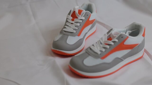 Pair of stylish white and orange sneaker on light background. Modern casual footwear for sport and everyday lifestyle. Fashion trend and comfortable shoe concept for athletic activity