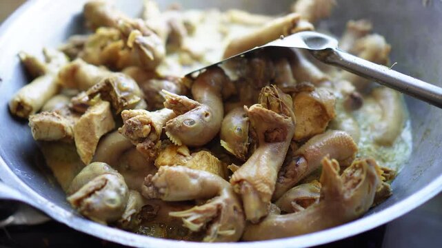 Close-up of chopped chicken pieces simmering in a pan with sauce and utensil, capturing rustic cooking moment for culinary or food preparation content, elegantly showcasing stir.