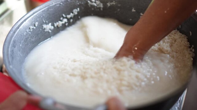 Close-up of hands mixing rice with liquid in a metal bowl traditional food preparation process natural texture focus on cooking technique, elegantly showcasing kitchen.