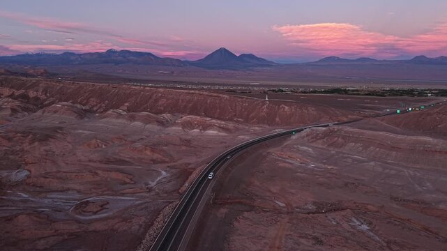Desert road through Atacama landscape at pink sunset