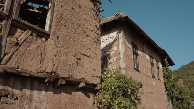 Close up shot showing wooden window frames and cracked mud wall of a traditional old house in Topli Do village, Stara Planina, Serbia. Cinematic detail of rustic Balkan architecture.