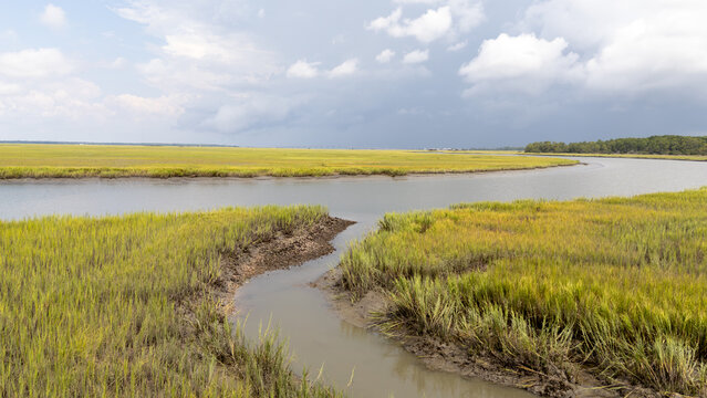 View of a marshland with winding waterway taken from a drone in a cloudy sky during the day