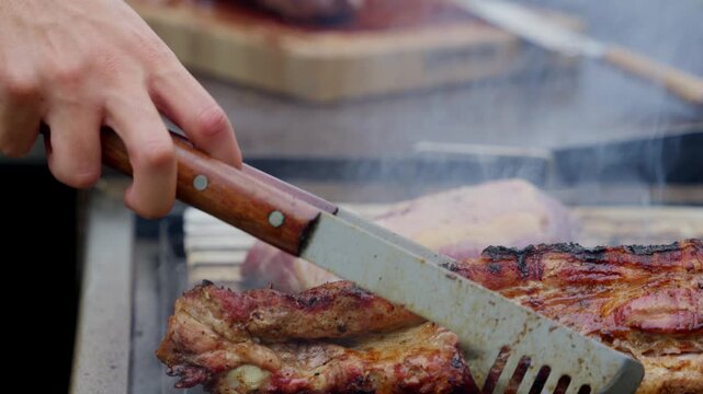 Chef grilling juicy pork ribs on barbecue grill in slow motion