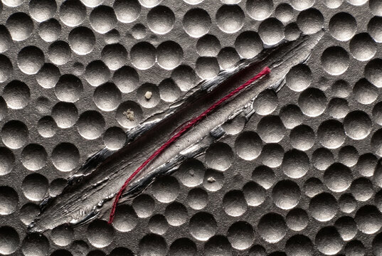 Torn black textured surface with red fibers and worn abstract detail
