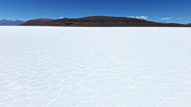 Salar de Uyuni salt flat beneath mountain and blue sky