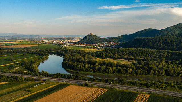 Aerial view of Deva Fortress overlooking the Mures River, surrounding forests, and agricultural fields in Deva, Hunedoara, Romania.