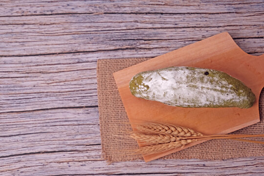 Fresh sourdough dusted with flour rests on wooden board. Golden wheat stalks lie beside it, adding rustic charm. Burlap cloth and warm tones create cozy kitchen ambiance. Perfect for food blogs