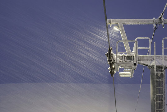 Snowy chairlift tower in winter ski resort wind
