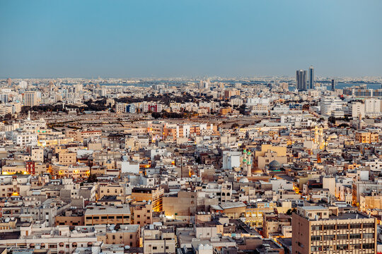 Aerial view of the dense urban landscape of Manama, featuring a mix of traditional and modern buildings, mosques, and narrow streets in Manama, Capital Governorate, Bahrain.