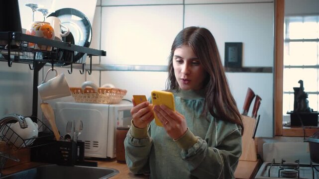 Young Latina woman in her kitchen shopping online with her credit card, making a digital purchase from home.
