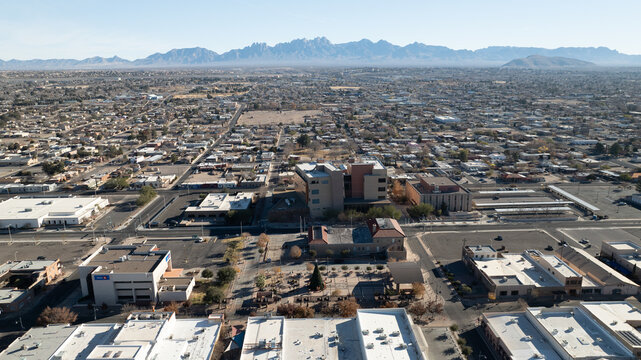 Las Cruces, United States - 17 December 2023: Aerial view of the city skyline with urban buildings, streets, and the Organ Mountains in the background under a clear sky.