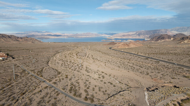 Boulder City, Nevada, United States - 24 December 2023: Aerial view of the desert landscape surrounding Lake Mead with winding roads, rugged mountains, and sparse vegetation.