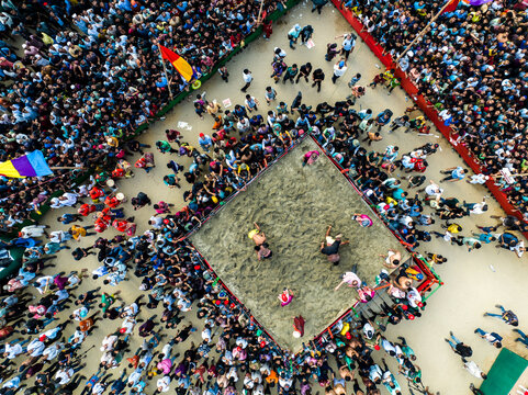 Chattogram, Bangladesh - 25 April 2024: Aerial view of the traditional Jabbar-er Boli Khela wrestling match in a square sand pit, surrounded by a large crowd of spectators.