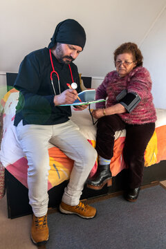 A man home health doctor writes a report after treating an active older woman