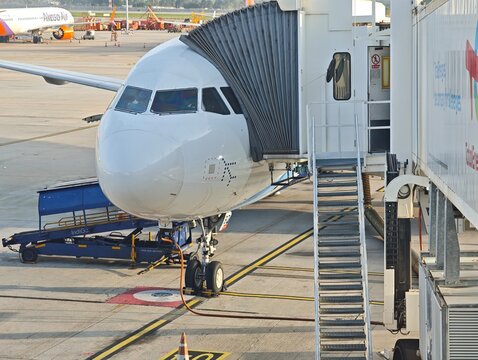 An IndiGo commercial aircraft is parked at Bangalore international airport gate connected to a jet bridge for passenger boarding or deboarding
