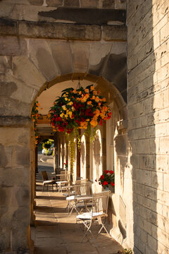 Cozy outdoor cafe terrace under ancient stone archway in historical British town at sunset light