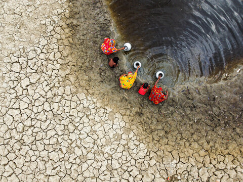 Shyamnagar, Khulna Division, Bangladesh - 14 August 2026: Aerial view of people collecting water from a muddy pond in a drought-stricken landscape.