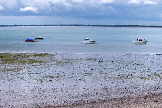 View of Cancale bay and boats during low tide in Brittany, with exposed seabed and tidal landscape of the bay, France