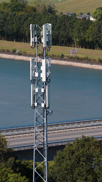Aerial view of a telecommunications tower standing near a road and a body of water surrounded by trees in Rijswijk, South Holland, Netherlands.