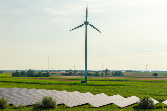 Aerial view of a wind turbine and solar panels in a green agricultural landscape in Poland.