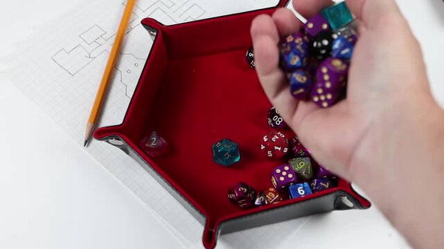 Rolling polyhedral gaming dice into a dice tray. Various colors and denominations of dice. 