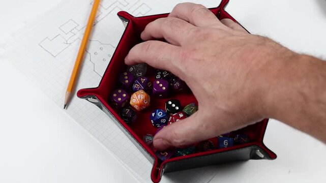 Rolling polyhedral gaming dice into a dice tray. Various colors and denominations of dice. 