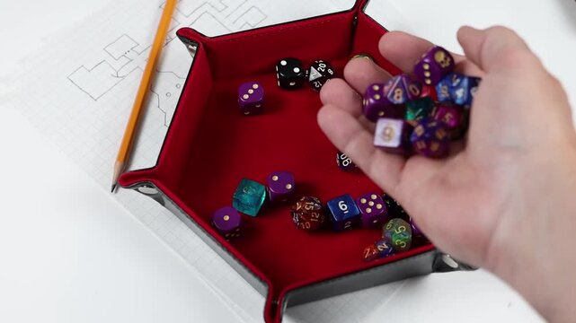 Rolling polyhedral gaming dice into a dice tray. Various colors and denominations of dice. 