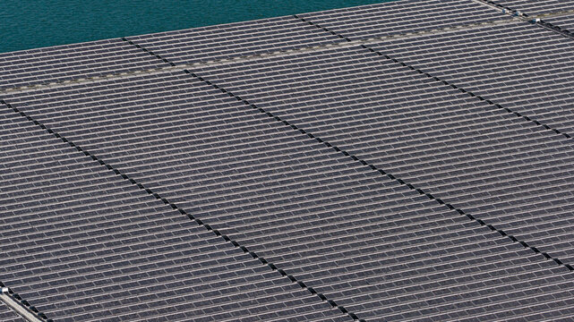 Aerial view of a large floating solar farm installed on a calm body of water, showcasing rows of photovoltaic panels in Echteld, Gelderland, Netherlands.