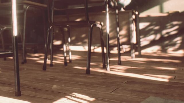 Chairs are arranged in a cozy cafe with sunlight streaming through the windows. Shadows stretch across the wooden floor. It is a busy afternoon as people enjoy their drinks.