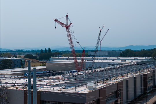 Aerial view of the Hillsboro data centers construction site featuring large industrial buildings, tall red cranes, and flat rooftops in Hillsboro, Oregon, United States.