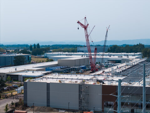 Aerial view of Hillsboro data centers construction site featuring large industrial buildings, tall cranes, and surrounding landscape in Hillsboro, Oregon, United States.