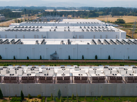 Aerial view of Hillsboro data centers with large white industrial buildings, extensive rooftop cooling units, and surrounding green landscaping in Hillsboro, Oregon, United States.