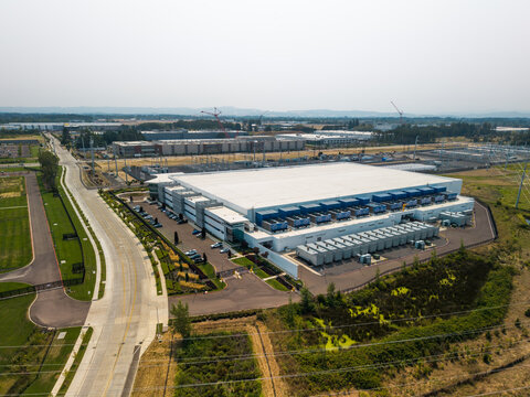 Aerial view of Hillsboro data centers featuring large industrial buildings, cooling units, surrounding roads, and green landscape in Hillsboro, Oregon, United States.