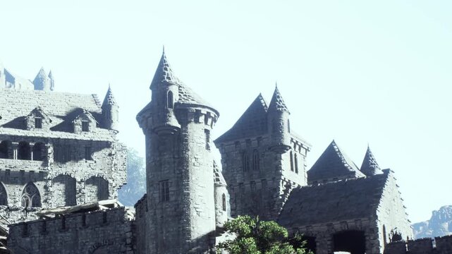 Rows of towers form a castle against the sky. The structure sits on a rocky surface in a hilly region. The stone walls reflect sunlight during daylight. Greenery surrounds the base.