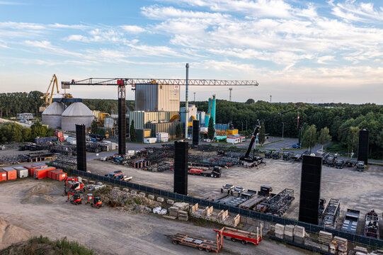 Aerial view of Kran Bau und Baustellenlogistik facility with a tower crane, industrial buildings, and a storage yard filled with construction equipment in Konigs Wusterhausen, Brandenburg, Germany.