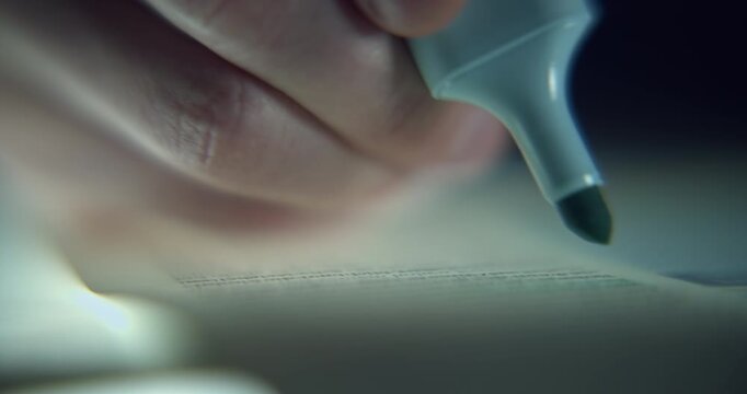 Extreme close-up footage of a man's hand highlighting lines of text with a blue highlighter, captured with a shallow depth of field and selective focus. Conceptual study and reading scene.
