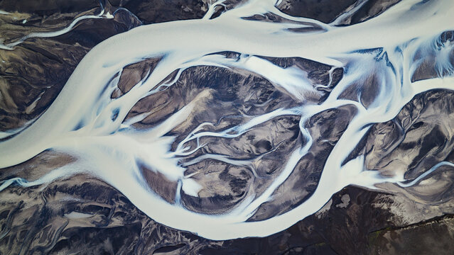Aerial view of the braided river Tungnaa with intricate glacial water channels flowing through dark volcanic sediment in Skaftarhreppur, Iceland.