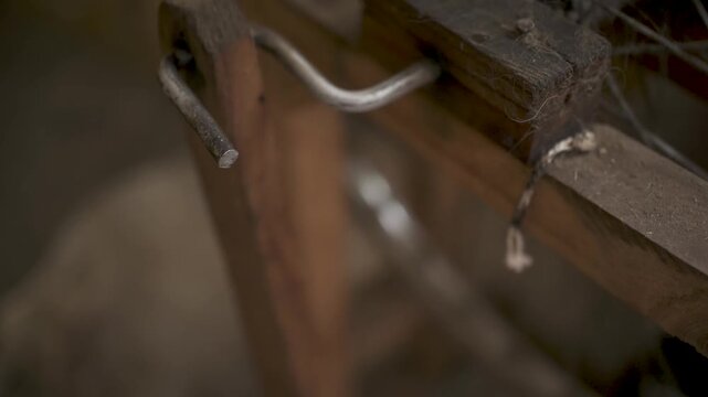 Close up of manual spinning wheel crank mechanism turning in a rustic workshop.