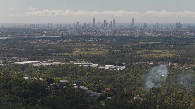 Aerial view of Surfers Paradise skyline from Gold Coast hinterland with smoke rising from forest.
