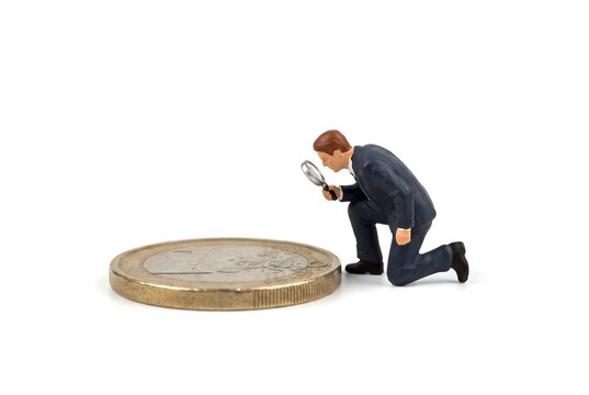1ユーロ硬貨にひざまずくビジネスマン