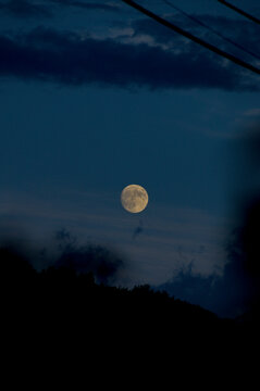  luminous full moon rising in a deep blue twilight sky