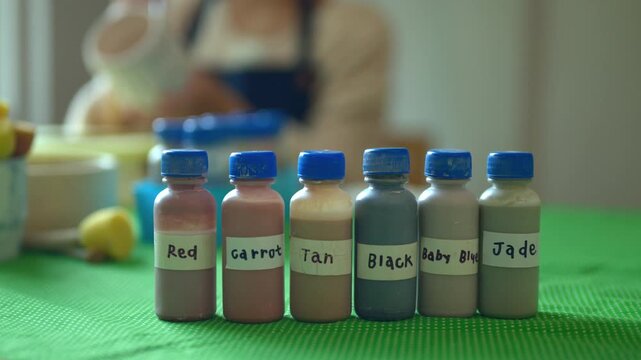 Labeled Color Pigment Bottles in Art Studio with Artist Working in Background