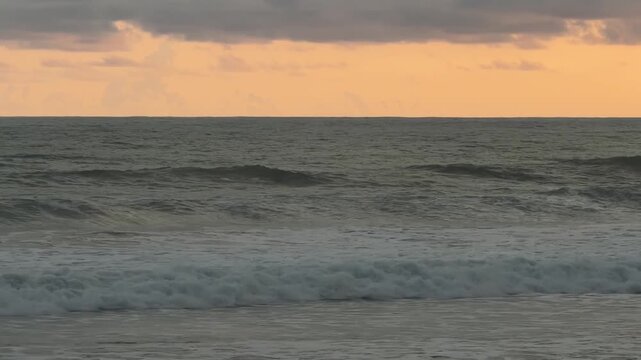 Sunset ocean waves rolling onto the shore