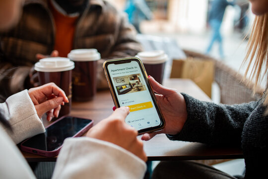 Travelers using smartphone for apartment check-in at a cafe