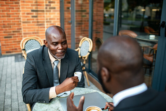 Two businessmen meeting over coffee at outdoor cafe