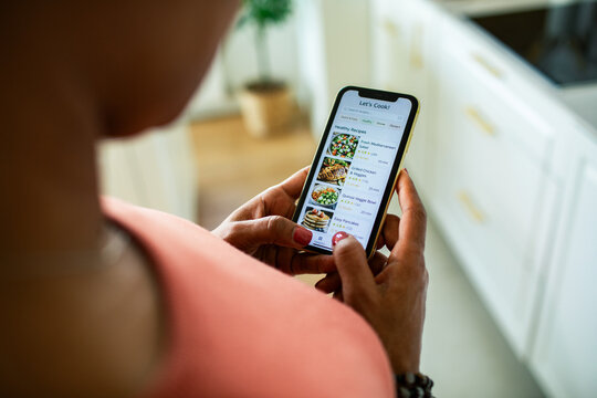 Woman browsing healthy recipes on smartphone in kitchen