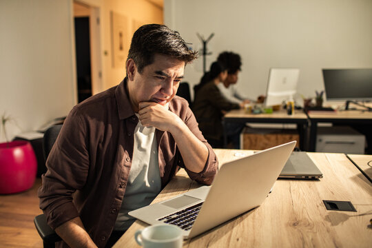 Concerned man working on laptop in modern office